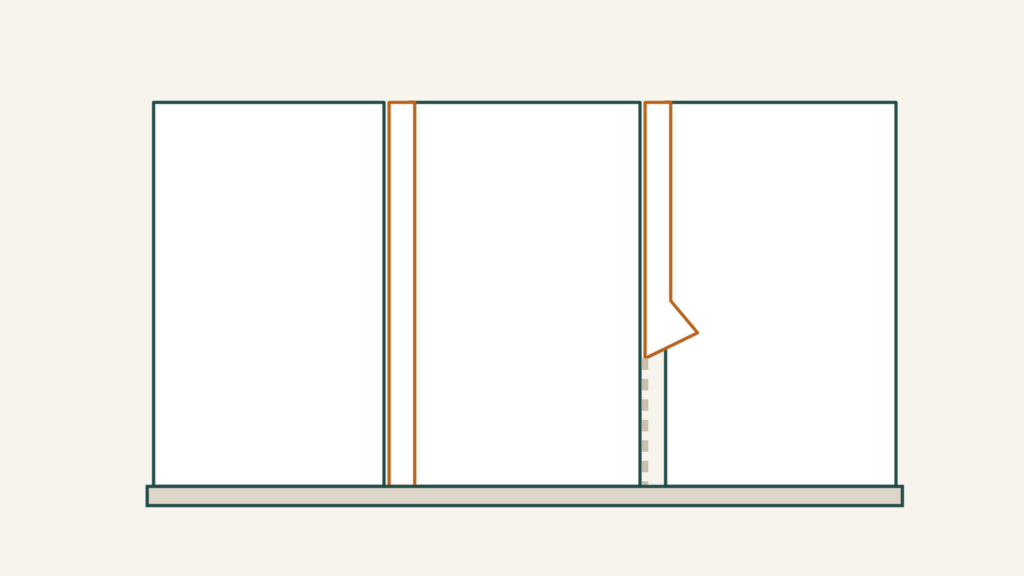 Mobile home wall strips covering the joints between vinyl over gypsum panels, with one strip lifted away